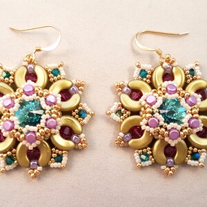 Puede incluir: Un par de pendientes de oro con un diseño de cuentas de color turquesa, rosa y blanco. Los pendientes tienen una forma floral y un gancho de oro.