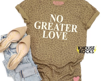 May include: A brown t-shirt with a leopard print pattern. The shirt has white text that says "No Greater Love".