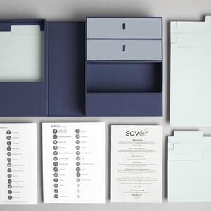 May include: A blue recipe box set with dividers, index cards, and instructions. The box has a drawer for storing recipe cards. The set includes a welcome guide and two sheets of recipe icons.
