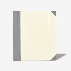 May include: A gray and cream-colored notebook with a gray spine and a cream-colored cover.