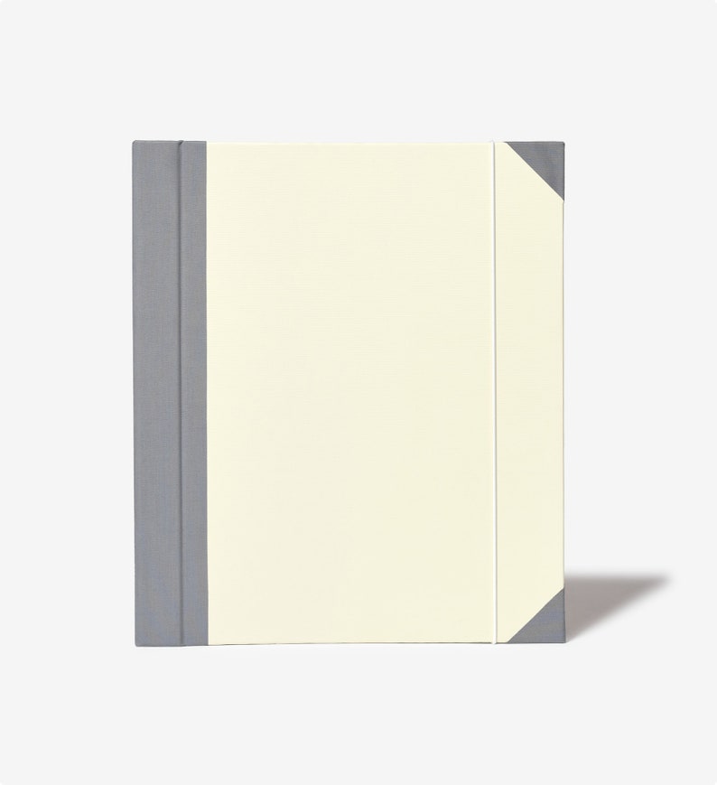 May include: A gray and cream-colored notebook with a gray spine and a cream-colored cover.