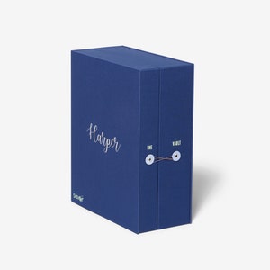 May include: A blue box with the text "Harper" and "The Vault" printed on it. The box has a string closure and is made of a textured material.