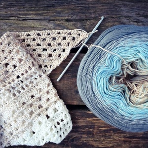 May include: A skein of blue, beige, and gray ombre yarn with a crochet hook and a crocheted scarf made with the same yarn.