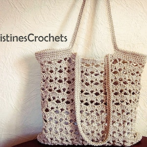 Könnte beinhalten: Eine gehäkelte Tragetasche in beige mit einem zarten Lochmuster. Die Tasche hat zwei lange Henkel und einen breiten Boden.