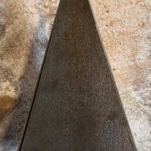 May include: A rustic metal wind chime featuring a triangle-shaped top with a sailboat design hanging from the bottom. The triangle is a dark brown color with a gold-colored top and the sailboat is a dark brown color with a gold-colored outline.