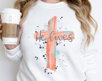 He lives watercolor cross tee. Jesus shirt. Bunny rabbit tee. Pastel shirt. Easter outfit. Easter egg hunt. Easter Sunday. Lent. He's risen