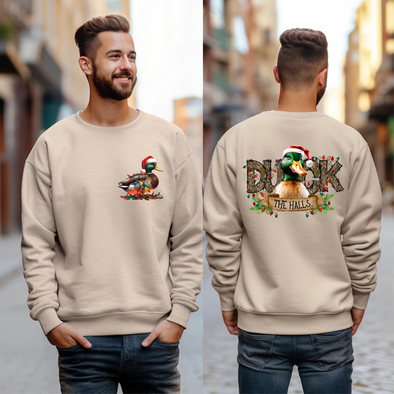 May include: A tan sweatshirt with a Christmas duck design on the front and a "Duck the Halls" design on the back.