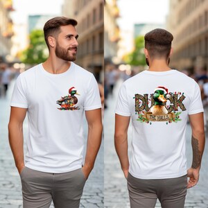 May include: White t-shirt with a Christmas duck design on the front and "Duck the Halls" text with a Christmas duck design on the back.