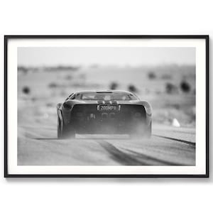 May include: Black and white framed print of a vintage sports car speeding down a road, kicking up dust. The car has a racing stripe and a license plate that reads "200MPH". The image is in black and white.