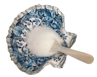 Puede incluir: Azúcar granulada blanca en un plato de cerámica en forma de concha de mar azul y blanco con una cuchara de madera blanca.