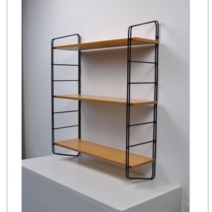 Peut inclure: Une étagère murale en métal noir avec trois étagères en bois. Les étagères sont en bois clair et sont soutenues par des supports en métal noir.