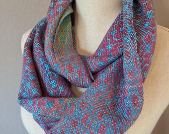 Bufanda infinita tejida a mano en fina mezcla de algodón Pima orgánico y lana de seda. Teñida a mano en vibrantes tonos turquesa, rojo, burdeos, naranja y amarillo.