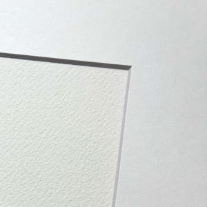 May include: Close-up of a white textured paper with a subtle gray border.