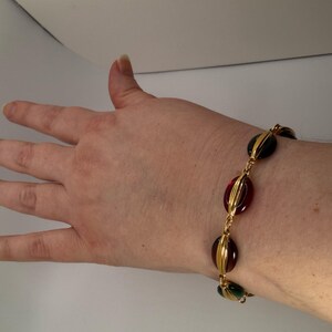 Puede incluir: Pulsera dorada con cuentas ovaladas rojas, verdes y negras. Las cuentas est&aacute;n engarzadas en metal dorado y unidas por una fina cadena. Un accesorio elegante para cualquier ocasi&oacute;n.