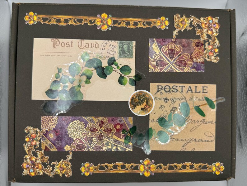 May include: A dark brown box decorated with vintage-style postcards, floral designs, and gold embellishments. The postcards feature botanical illustrations and the words "Post Card" and "Postale". Decorative gold borders and corner accents add a touch of elegance.