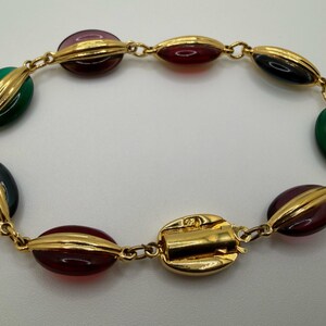 Puede incluir: Una pulsera dorada con cuentas ovaladas en tonos verdes, burdeos y negro. Las cuentas est&aacute;n separadas por detalles dorados y unidas por una delicada cadena. El cierre tambi&eacute;n es dorado.