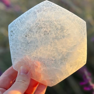 May include: A hexagonal clear selenite crystal with a cloudy white appearance. The crystal is smooth and polished.