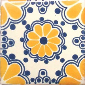 May include: A white ceramic tile with a blue and yellow floral pattern. The tile features a large yellow flower with a blue center surrounded by smaller yellow flowers and blue dots.