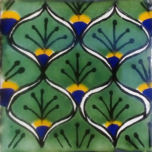 May include: A green ceramic tile with a repeating pattern of white, blue, and yellow stylized flowers. The tile has a glossy finish.