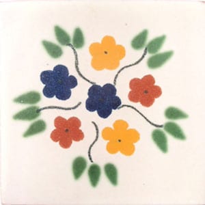 May include: A white ceramic tile with a floral design. The design features five flowers in shades of yellow, orange, blue, and red. The flowers are surrounded by green leaves.