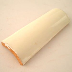 May include: A curved, off-white ceramic tile with a slightly rounded edge. The tile has a smooth, glossy finish.