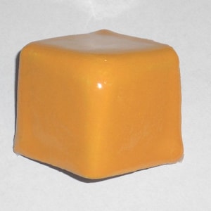 May include: A square, orange-yellow object with rounded corners. The top surface has a lighter, glossy appearance. The object is set against a plain white background, highlighting its shape and color.
