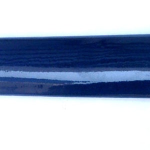 May include: A dark blue ceramic tile with a rounded edge. The tile has a glossy finish and a subtle woodgrain pattern.