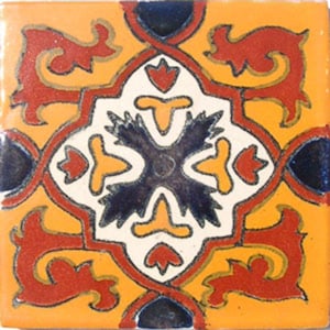 May include: A square ceramic tile with a colorful geometric pattern. The tile features a central design of a four-pointed star with a dark blue center, surrounded by yellow, orange, and red accents. The tile is framed by a border of intricate floral designs in shades of red, orange, and yellow.