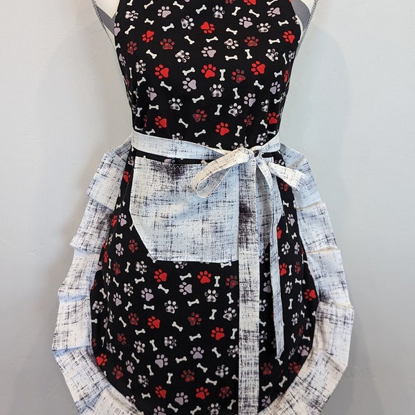 Adult apron. Woman's apron. Red and gray puppy paws and white bones on black. White with black haze on pocket, ties and frills.