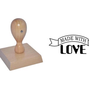 May include: Wooden rubber stamp with a brown handle and a square base. The stamp reads "Made with Love" in a banner design.