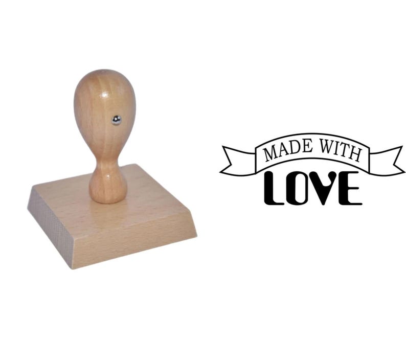 May include: Wooden rubber stamp with a brown handle and a square base. The stamp reads "Made with Love" in a banner design.