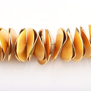 May include: A gold necklace made of overlapping, rounded, and textured metal pieces.