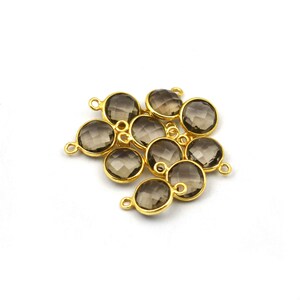 May include: A group of ten gold-toned metal charms with smoky quartz gemstones. Each charm has a round, faceted gemstone with a loop on the top for attaching to jewelry.