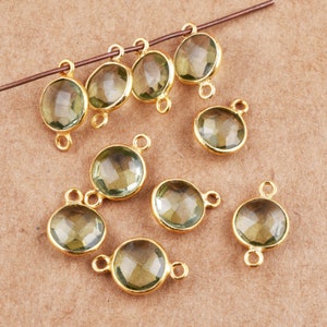 May include: Ten gold-toned metal connector charms with clear green faceted gemstones. Each charm has two loops for attaching to jewelry.