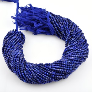May include: A strand of deep blue lapis lazuli gemstone beads, faceted and round, strung on a blue cord with a tassel.