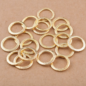 Könnte beinhalten: Ein Haufen goldfarbener Metall-Sprünge. Die Ringe sind alle gleich groß und haben eine strukturierte Oberfläche.