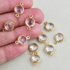 May include: Ten clear glass round beads with gold-toned metal loops on each side. The beads are faceted and have a shiny finish.