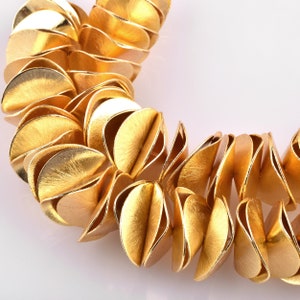 May include: A gold necklace made of overlapping, textured, leaf-shaped links.