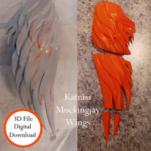 May include: 3D printed model of Katniss Everdeen's Mockingjay wings from the Hunger Games. The wings are orange and are printed in separate pieces. The image also includes text that says "Katniss Mockingjay Wings" and "3D File Digital Download".