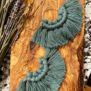 May include: A pair of teal blue tassel earrings with silver hoops. The earrings are handmade and feature a fringe design.