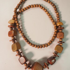 May include: A brown wooden necklace with large, square beads and smaller round beads.
