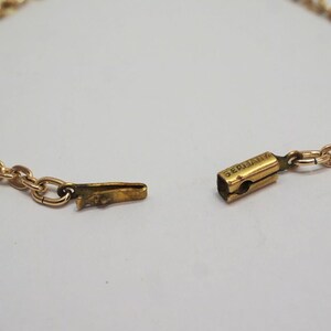 May include: Close-up of a gold-colored necklace with a chain link design. The clasp is open, revealing the intricate details of the chain and the clasp mechanism. The word "GERMANY" is visible on the clasp.
