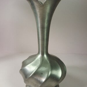 May include: A silver pewter vase with a fluted design and a flared opening. The vase is about 8 inches tall.