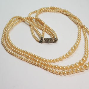 Puede incluir: Collar de tres hilos con perlas de imitaci&oacute;n de diferentes tama&ntilde;os, color crema. El cierre es plateado. Los hilos est&aacute;n dispuestos en cascada, creando un aspecto cl&aacute;sico y elegante. Una joya atemporal, perfecta para cualquier ocasi&oacute;n.