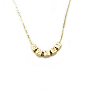 Peut inclure: Un collier en or avec une chaîne et un pendentif qui épelle le nom "DONNA" en lettres majuscules.