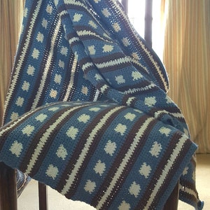 May include: A blue, white, and brown crocheted throw blanket with a star pattern draped over a wooden chair.