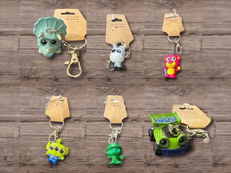 Puede incluir: Colecci&oacute;n de llaveros de personajes, que incluyen un dinosaurio verde, un burro gris, un oso rosa, un extraterrestre verde, un extraterrestre verde y un coche verde. Cada llavero est&aacute; unido a una etiqueta marr&oacute;n con las palabras "Handmade with love".