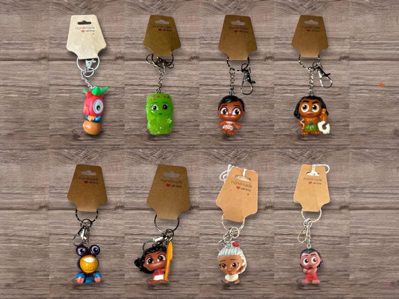 Puede incluir: Una colecci&oacute;n de llaveros de personajes con etiquetas de cart&oacute;n marr&oacute;n. Los llaveros presentan varias figuras de dibujos animados coloridas, unidas a llaveros plateados. El fondo es una superficie de madera.