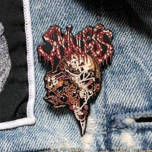 Pin oficial de Savagery: sin piel, coleccionable de Death Metal aplastante