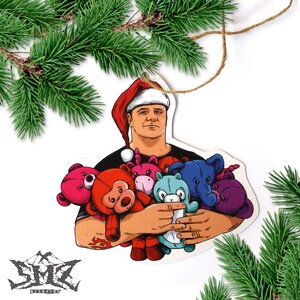 May include: A Christmas ornament featuring a man wearing a Santa hat holding a group of colorful plush toys. The man is wearing a black shirt and has a beard. The toys include a pink bear, a red monkey, a purple unicorn, a blue elephant, a light blue bear, and a purple bear.